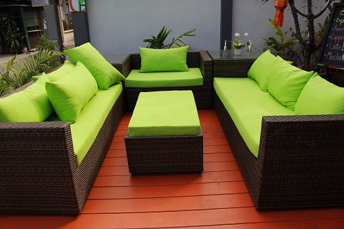 Outdoor seating set with green cushions on a wooden deck.