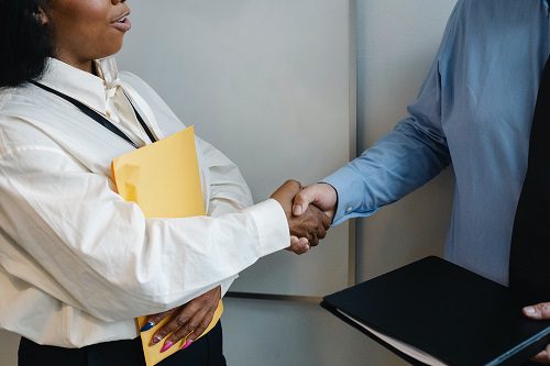 Two professionals shaking hands in an office setting.