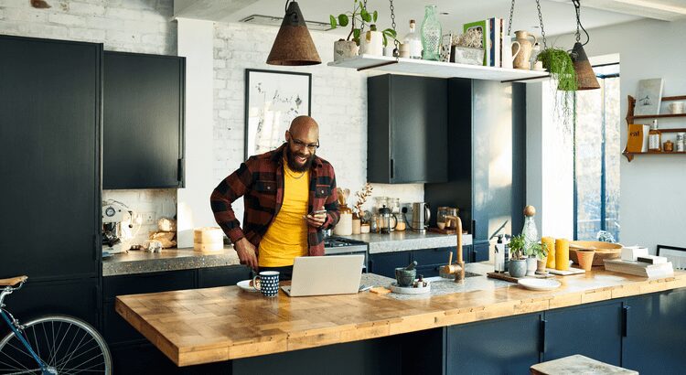 Man working on a laptop in a modern kitchen.