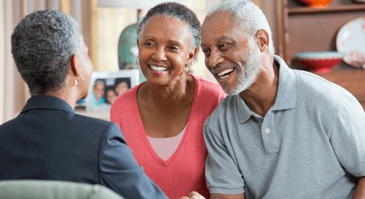 Smiling elderly couple engaged in conversation with a professional.