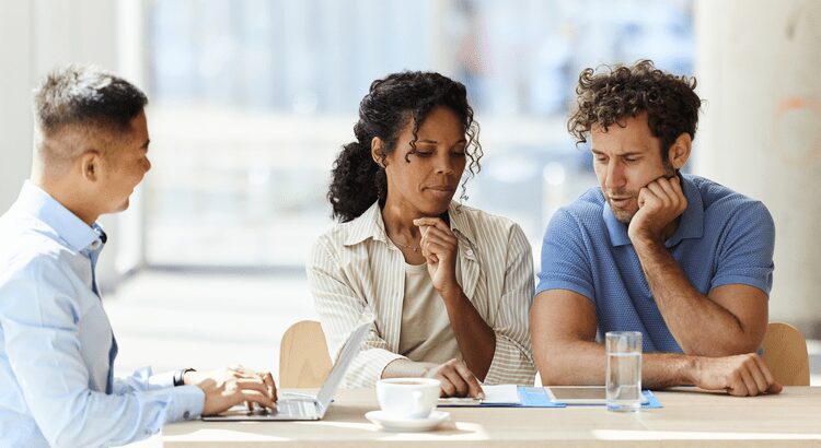 Three colleagues engaged in a serious discussion in a bright office.