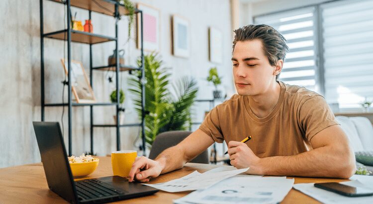 Young man working at a desk with documents and a cup of coffee.