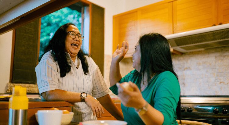 Two women laughing and enjoying a lively conversation indoors.