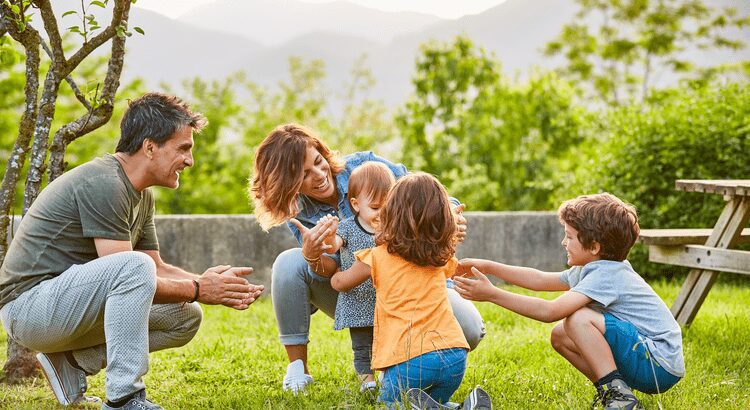 Family enjoying playful moments together outdoors on a sunny day.