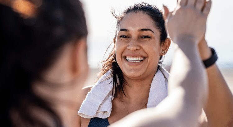A woman smiling brightly with a towel around her neck.
