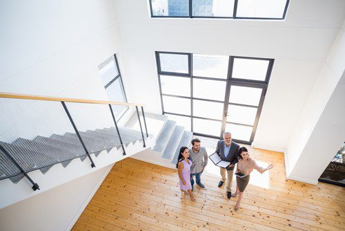 A family walks up a bright staircase with large windows.