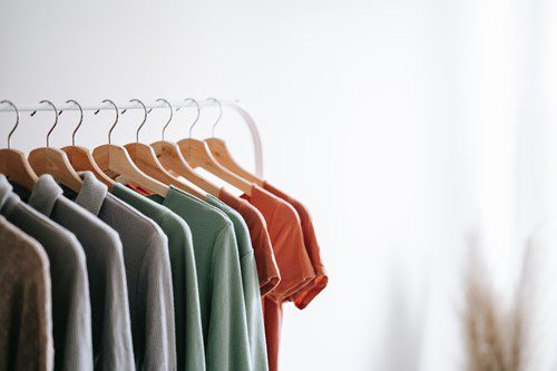 Clothes hang neatly on wooden hangers against a white background.