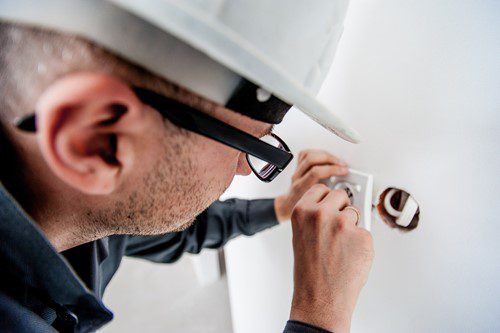 Electrician working on wiring inside a wall socket.
