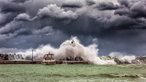 Dramatic waves crash over a pier under stormy skies.