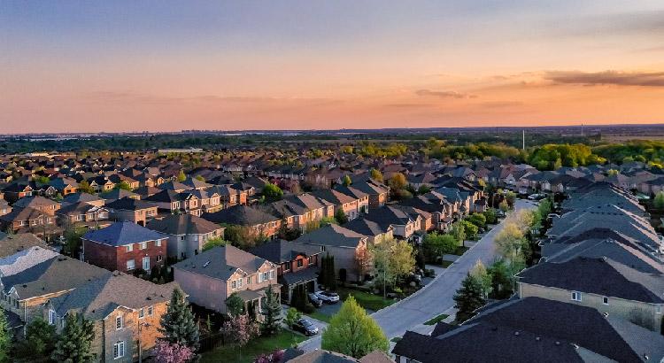 A suburban neighborhood at sunset with rows of houses and tree-lined streets.