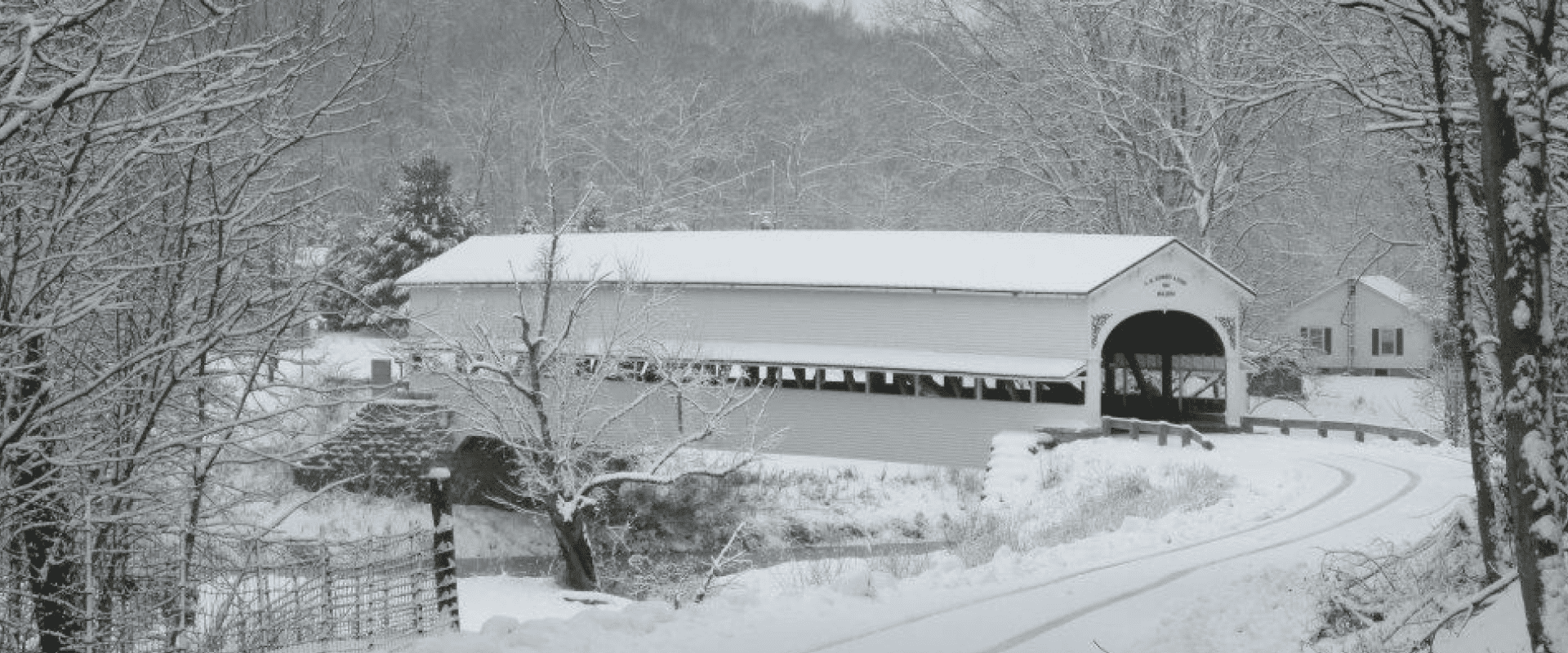 Snow-covered covered bridge in a serene winter landscape.