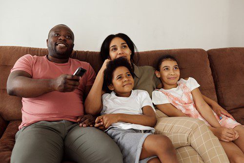 Happy family watching TV together on the couch.
