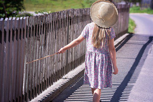 Little girl in a sunhat walking along a bridge on a sunny day.