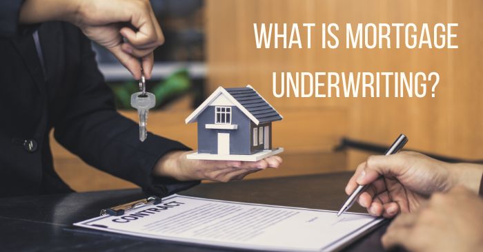 Person holding house key and model with contract on table asking about mortgage underwriting.