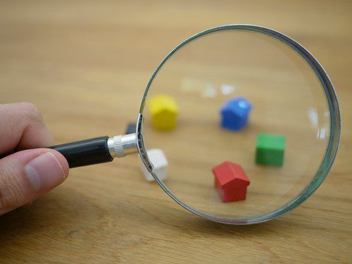 Magnifying glass focusing on colorful game pieces on a wooden surface.