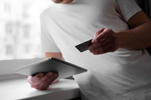 Person making an online payment using a tablet and credit card.