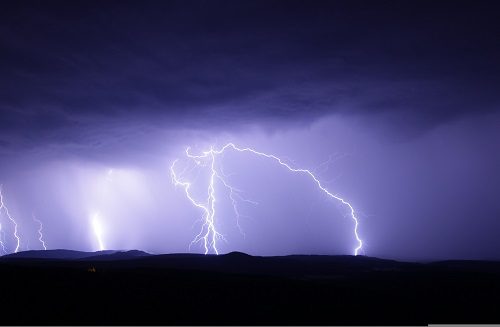 Bright lightning bolts illuminate the dark stormy sky.