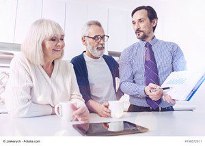 Three business professionals discussing work around a table with a tablet device.
