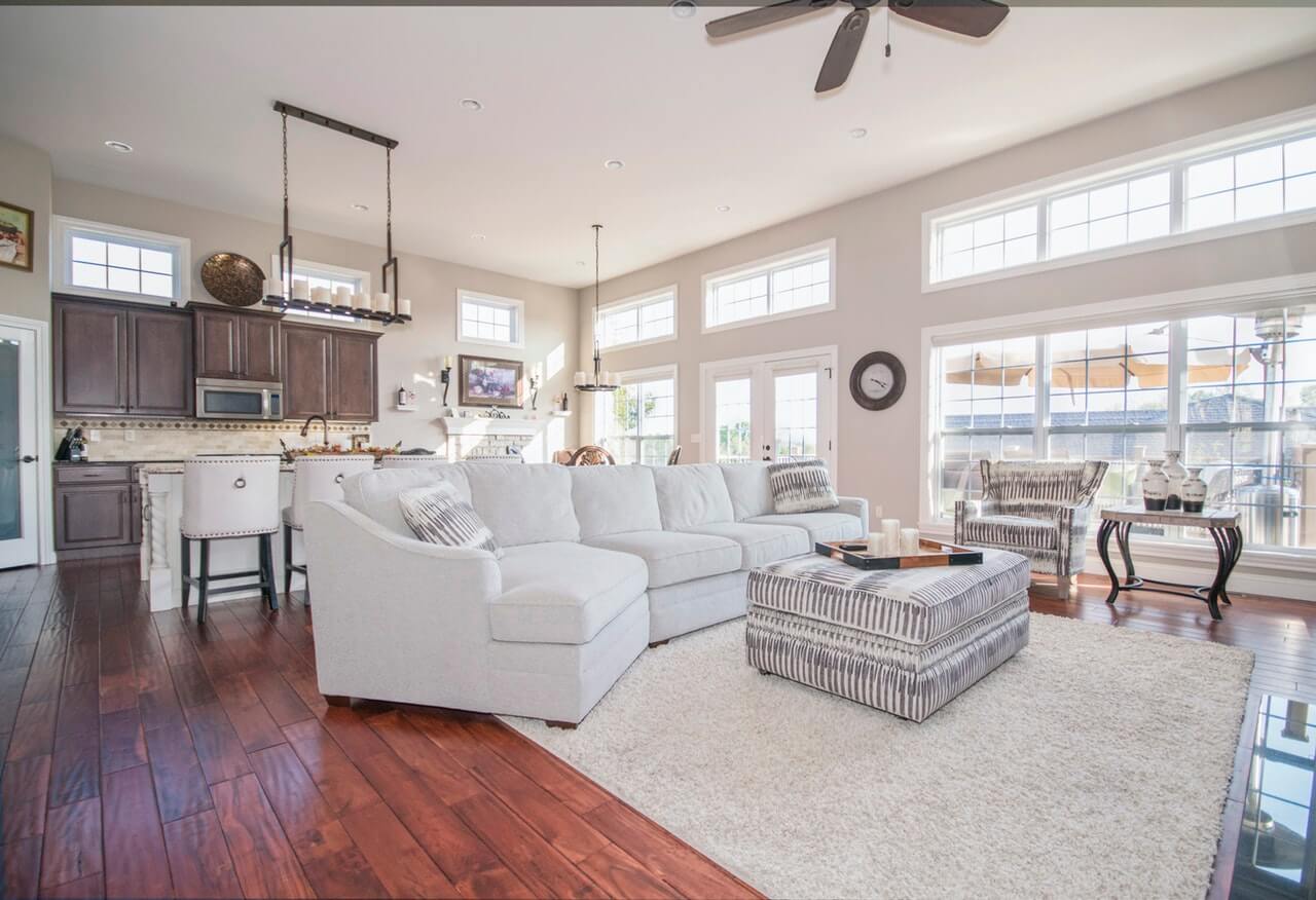 elevate-tips-selling Bright living room with white sectional sofa and wooden flooring.