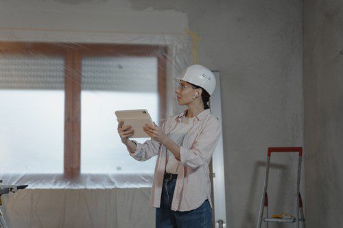 A woman in a hard hat inspecting a tablet in a construction site.